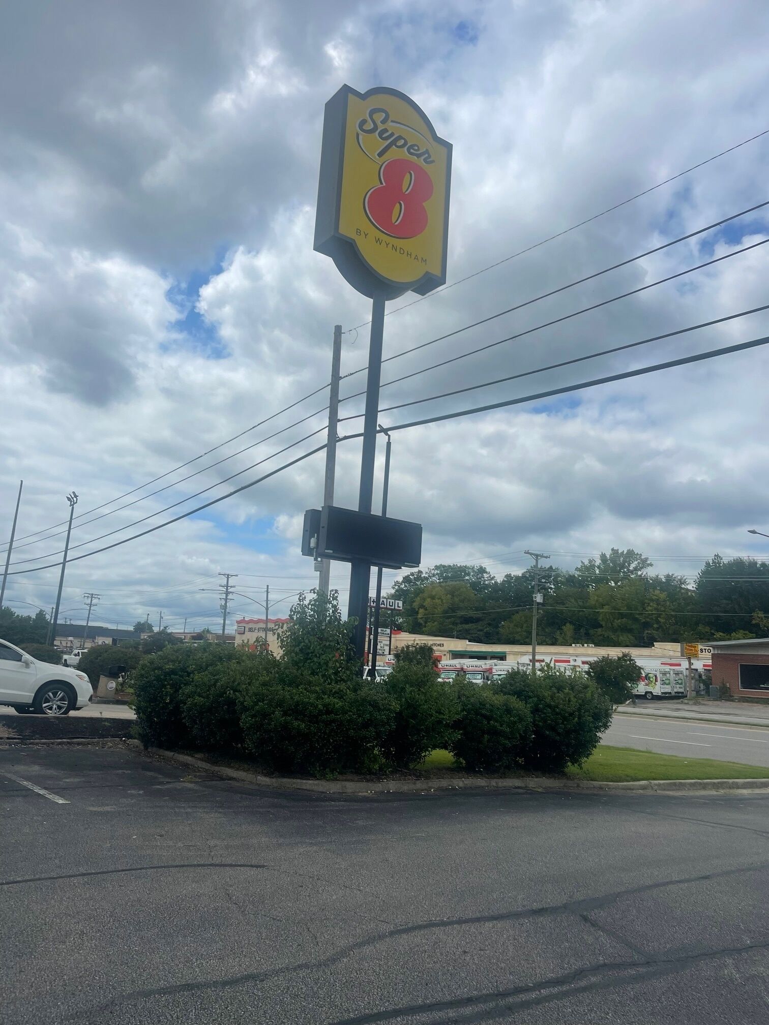 Señal de motel Super 8 con una vista clara de los alrededores, que incluye un estacionamiento y edificios cercanos.