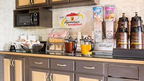 Una barra de desayuno con un cartel que dice 'Superstart breakfast', máquinas de café, un hervidor y dispensadores de cereales.