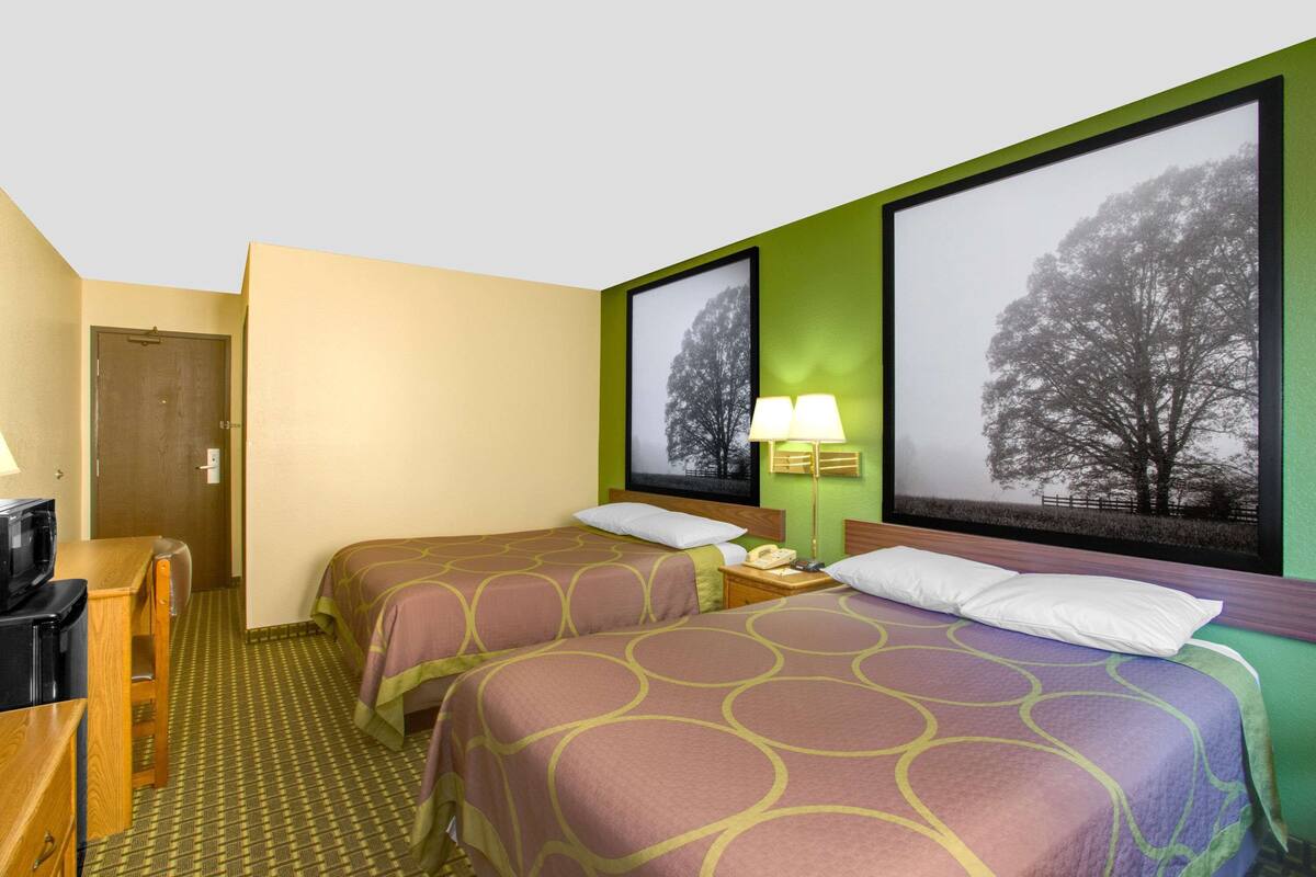 Une chambre d’hôtel avec deux lits, un bureau, une chaise, une lampe et un téléviseur.