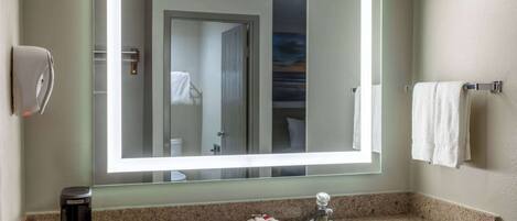 A bathroom with a large mirror, a sink, a towel rack, and a hand dryer.