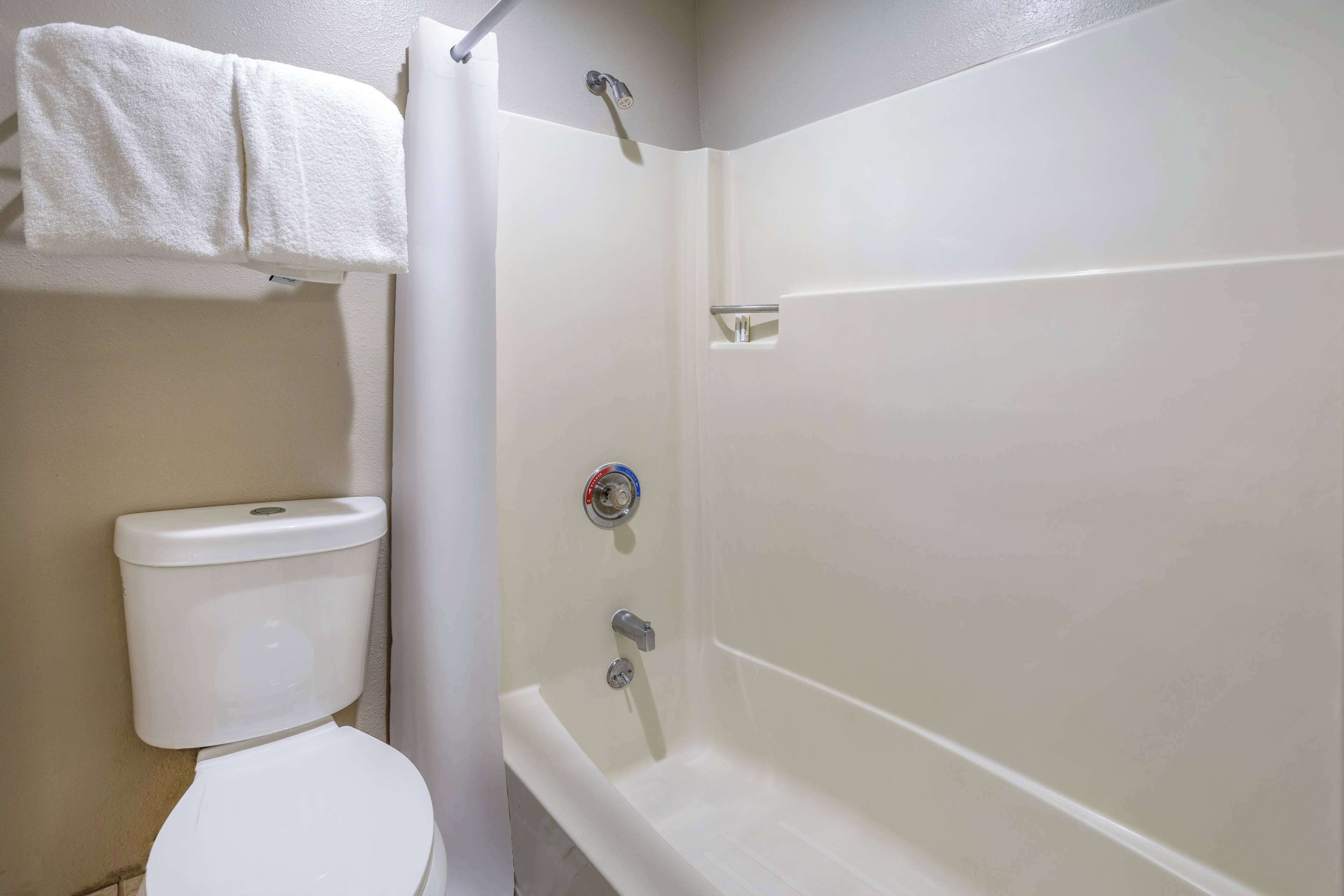 A bathroom with a toilet, a shower, and a towel rack.