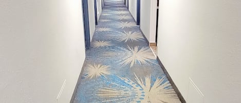A long, narrow hallway with a patterned carpet and white walls.