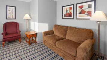 A living room with a brown sofa, a red armchair, a small wooden table, and two floor lamps.