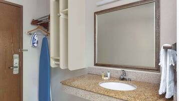 A bathroom with a granite countertop, a white sink, a large mirror, and a towel hanging on the wall.