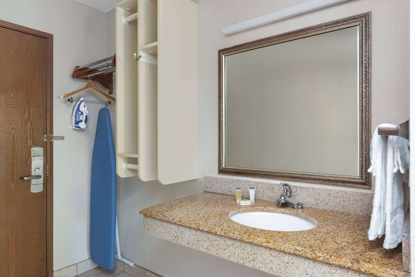 Une salle de bain avec un comptoir en granit, un lavabo blanc, un grand miroir et une serviette accrochée au mur.