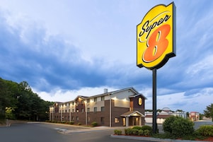 Um hotel Super 8 com uma grande placa, vários andares e estacionamento.