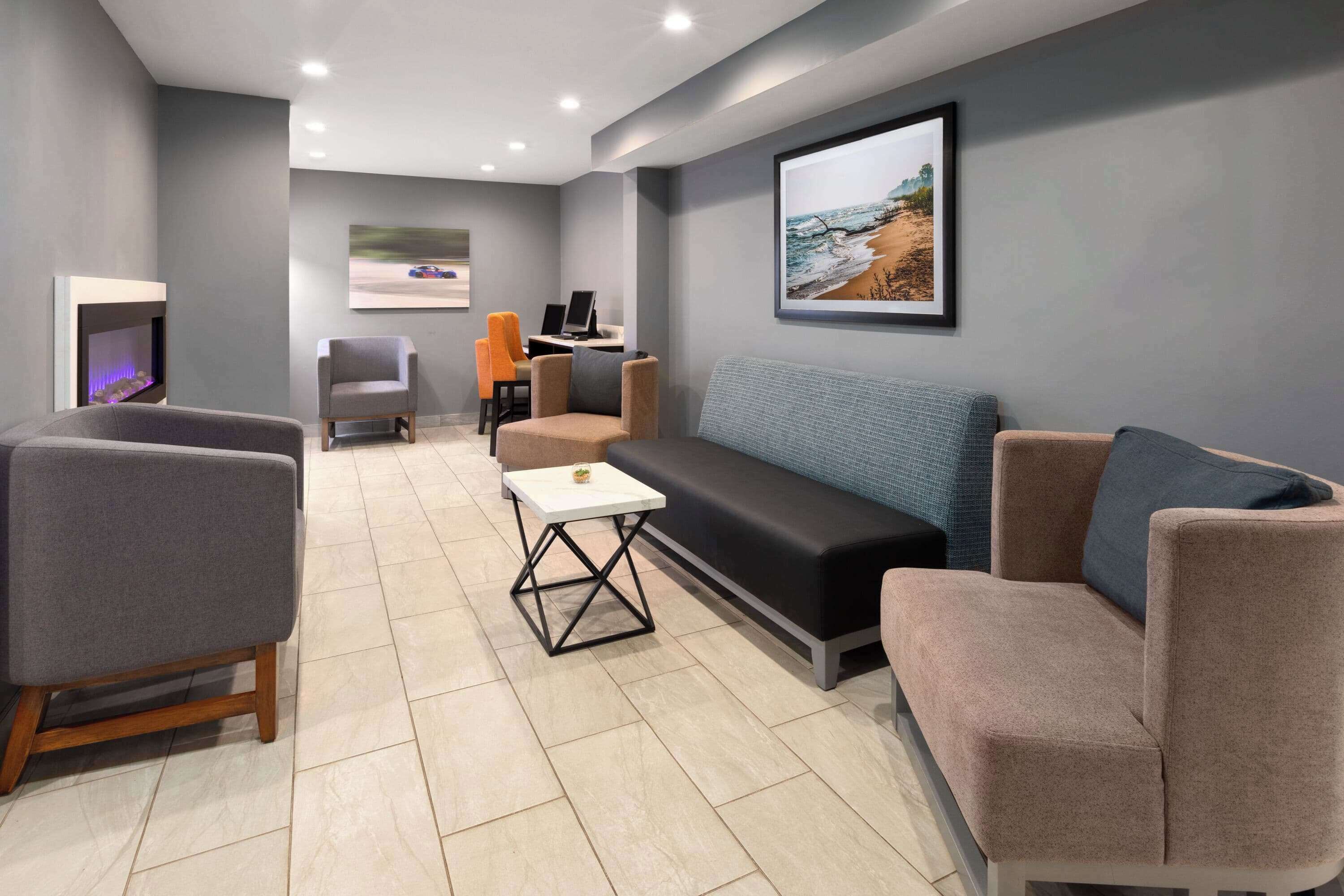 A modern lounge area with a fireplace, seating, and a desk with a laptop.