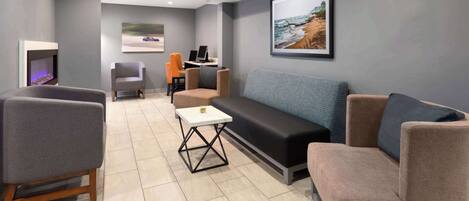 A modern lounge area with a fireplace, seating, and a desk with a laptop.