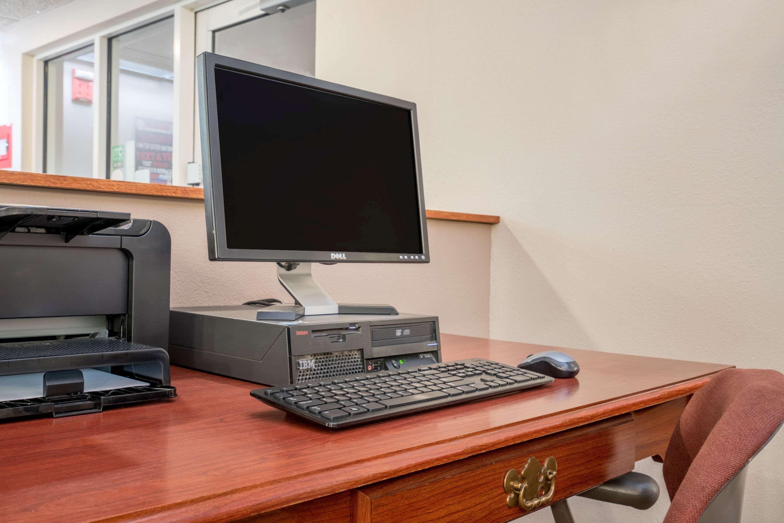 A wooden desk with a desktop computer, keyboard, mouse, and printer.