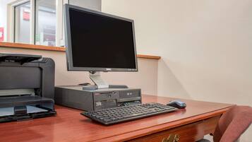A wooden desk with a desktop computer, keyboard, mouse, and printer.