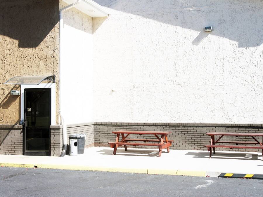 Un área de estacionamiento con mesas de picnic y la entrada a un edificio.