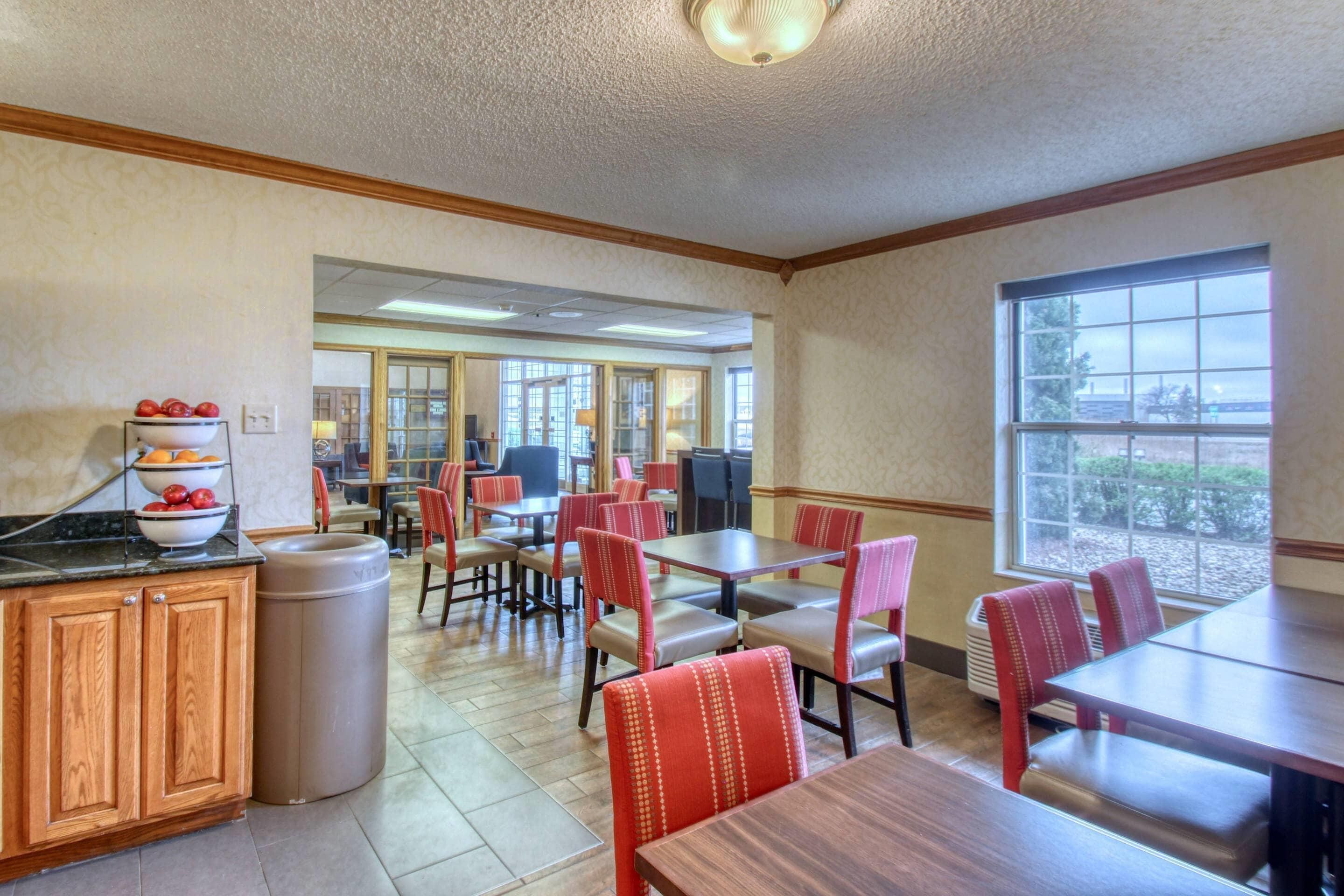 A restaurant with wooden cabinets, a trash can, and red chairs.