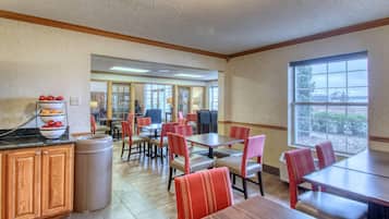A restaurant with wooden cabinets, a trash can, and red chairs.