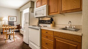 A compact kitchen with wooden cabinets, a microwave, stove, refrigerator, and a sink. - Comfort Inn Fond Du Lac (Fond du Lac)