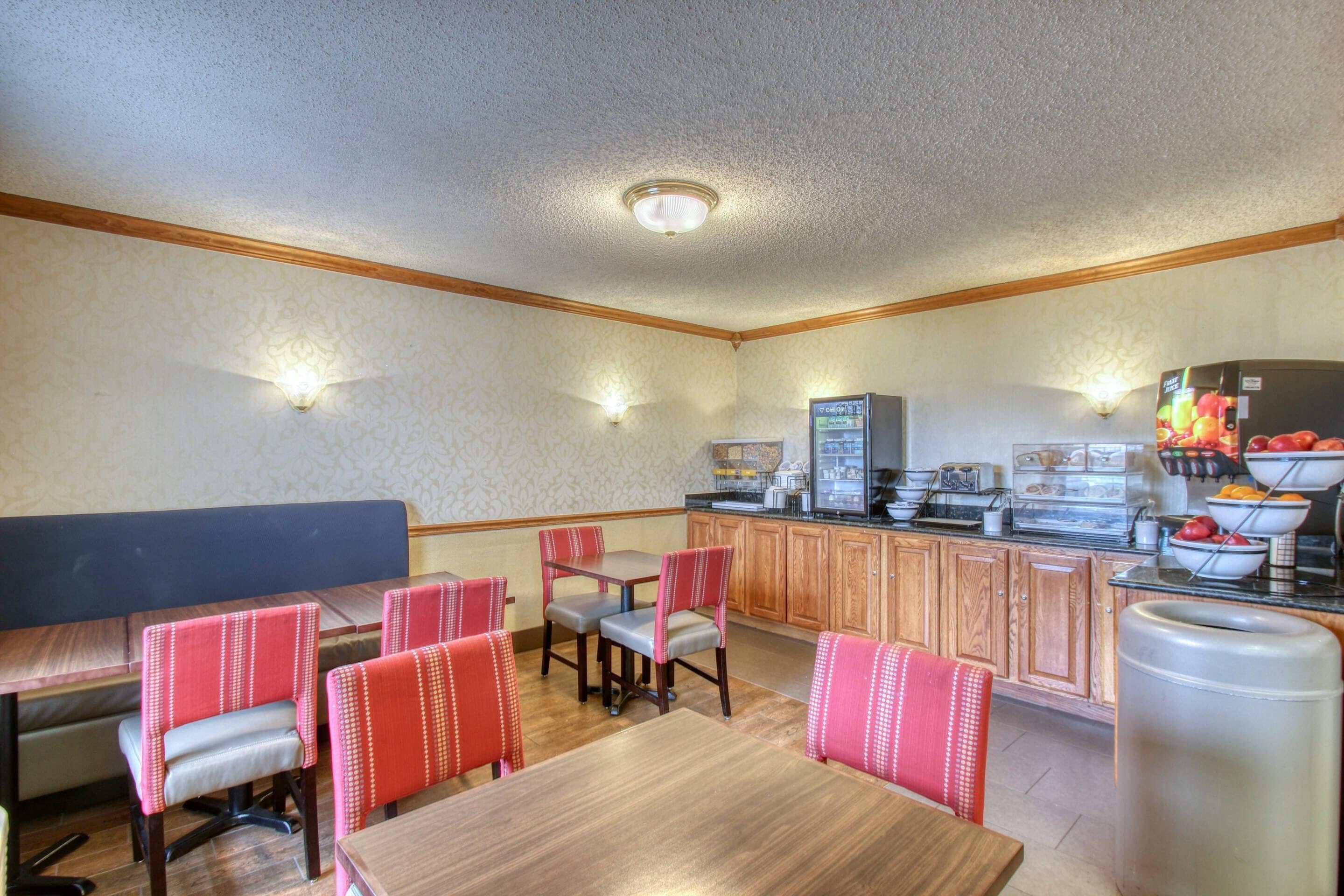 A dining area with wooden tables and chairs, a kitchen area with appliances, and a counter with food items.