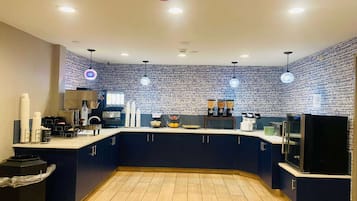 A modern kitchen with dark blue cabinets, a central island, and a brick-patterned backsplash.