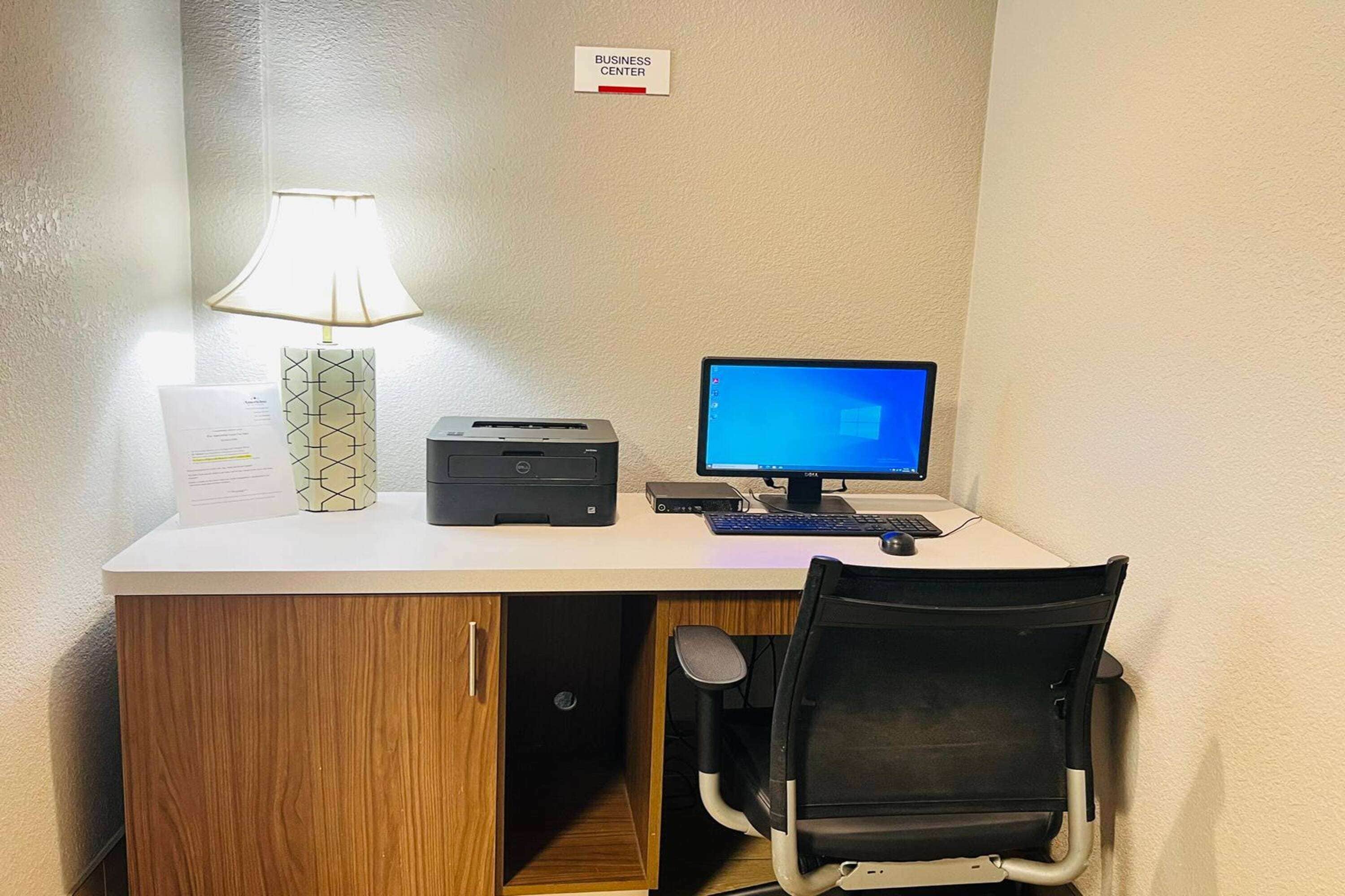 Escritorio de centro de negocios con computadora, impresora y lámpara.