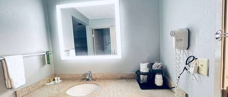 A bathroom with a sink, mirror, towel rack, and a hairdryer on the wall.