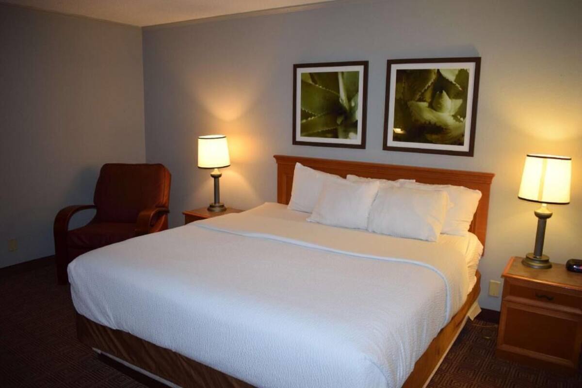 Ein Hotelzimmer mit einem Bett, zwei Nachttischen, einem Sessel und zwei Wandlampen.