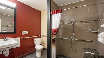 A bathroom with a shower, toilet, sink, and a mirror.