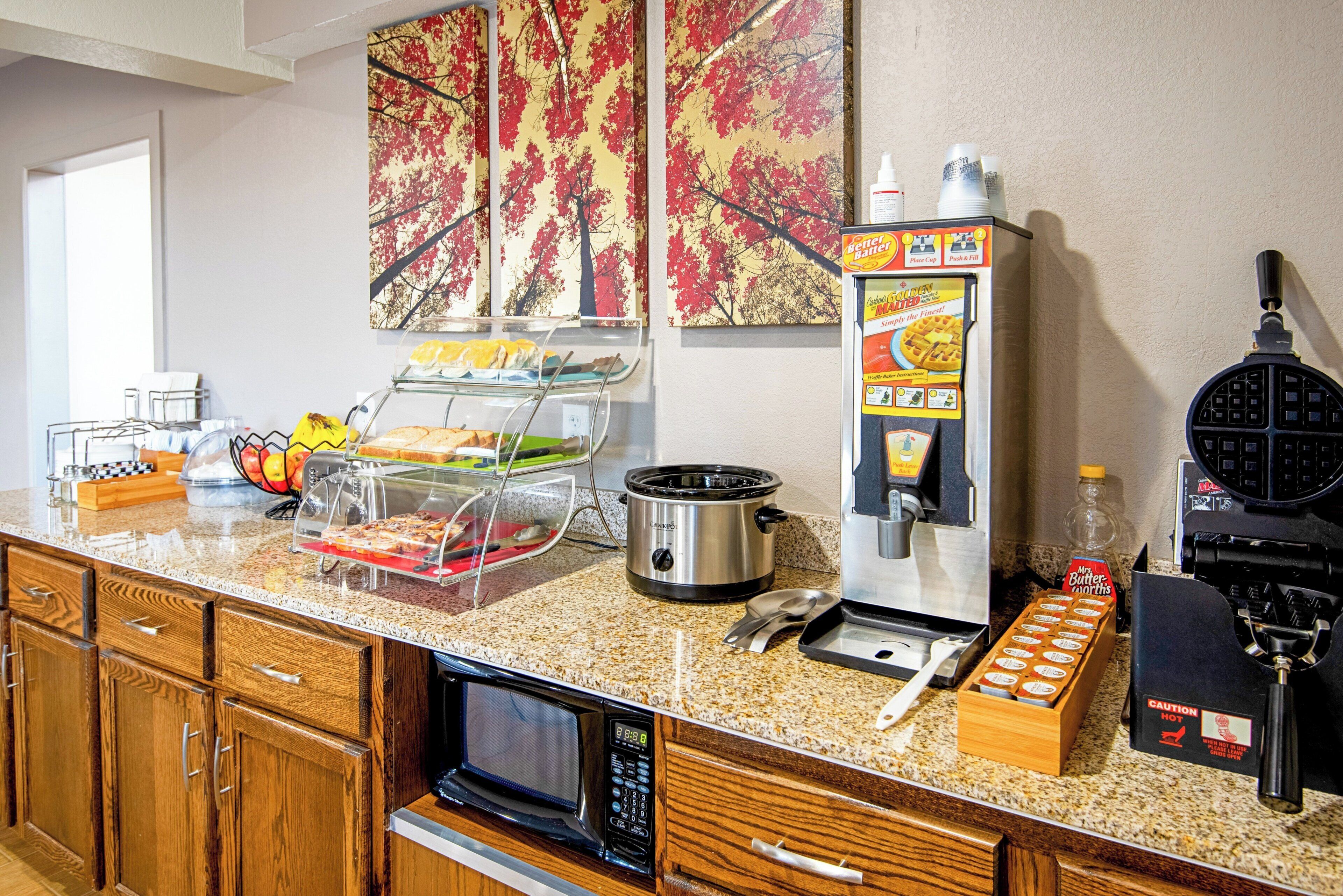 A kitchenette with a microwave, toaster, waffle maker, and coffee machine.