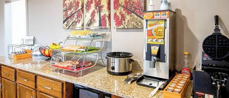 A kitchenette with a microwave, toaster, waffle maker, and coffee machine.