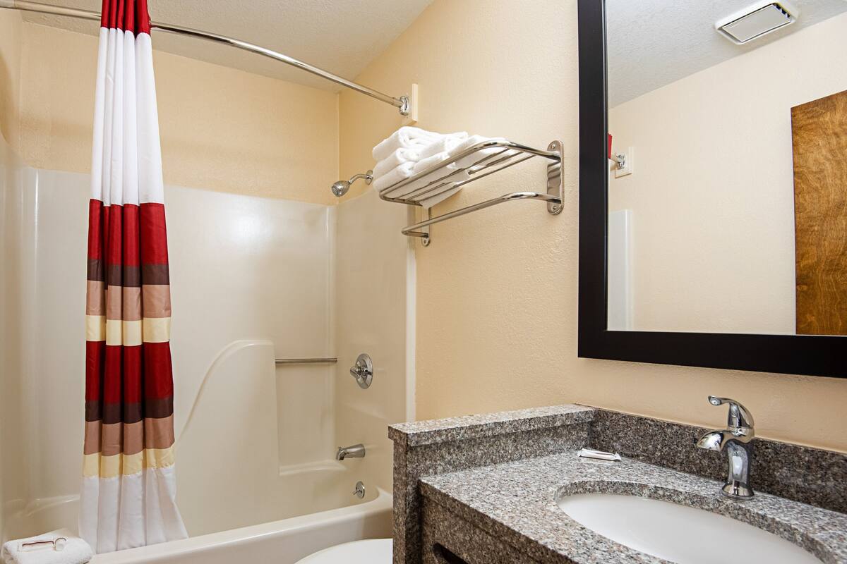 A bathroom with a shower, a sink, and a towel rack.