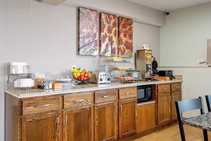 Una cocina con armarios de madera, un tostador, un frutero y un fabricante de gofres.