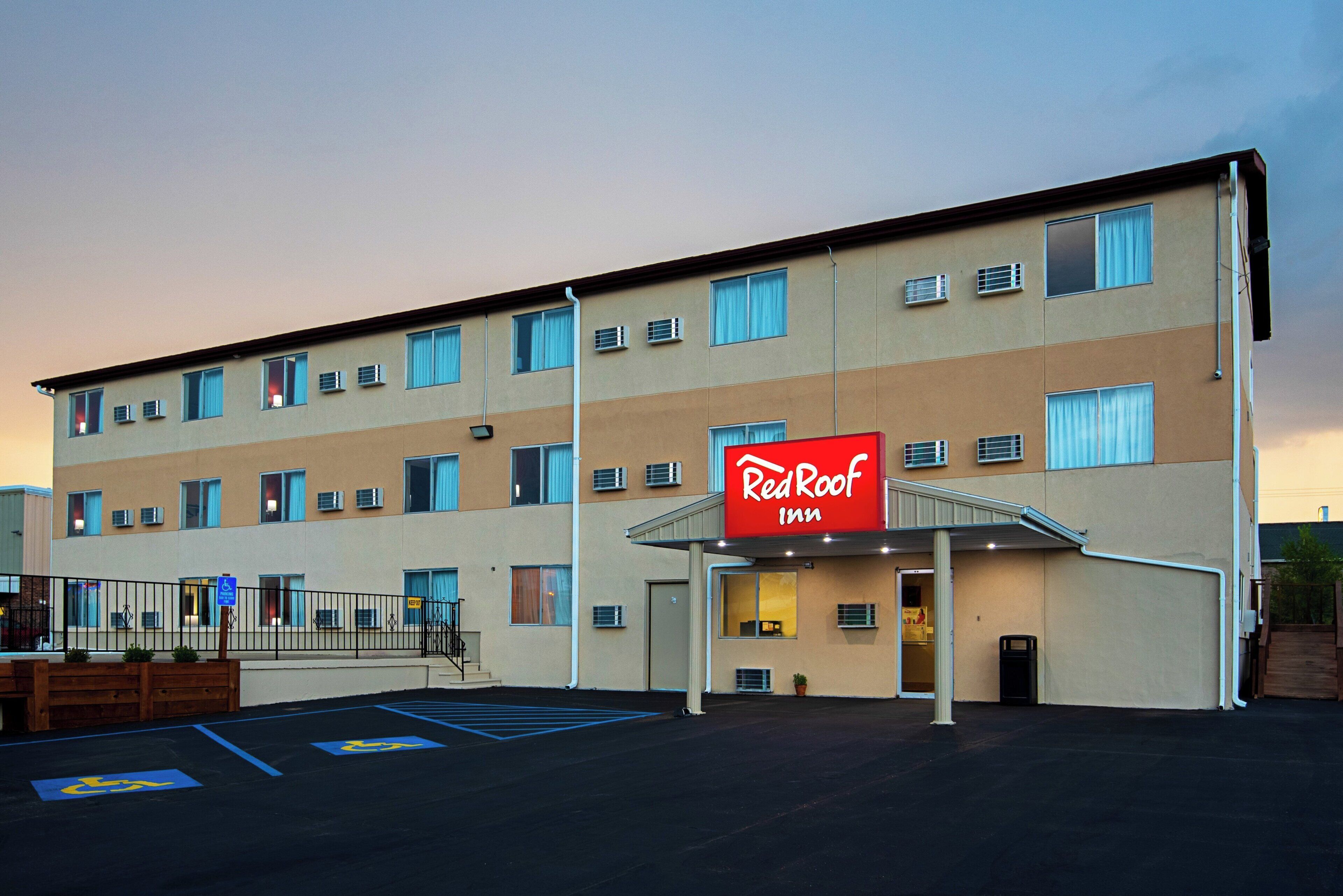 A Red Roof Inn with a flat facade, multiple windows, and a parking lot with handicapped parking spaces.