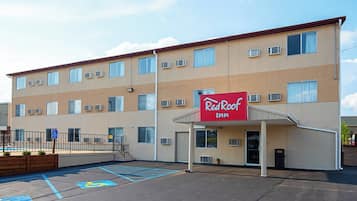 Un Red Roof Inn con estacionamiento, espacios reservados para discapacitados y un edificio con múltiples ventanas y unidades de aire acondicionado.