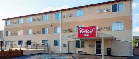 Ett Red Roof Inn-hotell med en parkeringsplats, handikappanpassade parkeringsplatser och en byggnad med många fönster och luftkonditioneringsanläggningar.