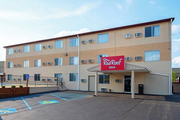 Un Red Roof Inn con parcheggio, posti auto riservati ai disabili e un edificio con numerose finestre e condizionatori.