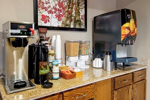 A coffee station with a coffee machine, creamer dispensers, and a juice dispenser.