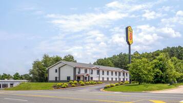 A motel with a large sign, a parking lot, and a building with a red roof.