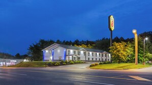 Un motel con un letrero grande, una entrada bien iluminada y un estacionamiento.