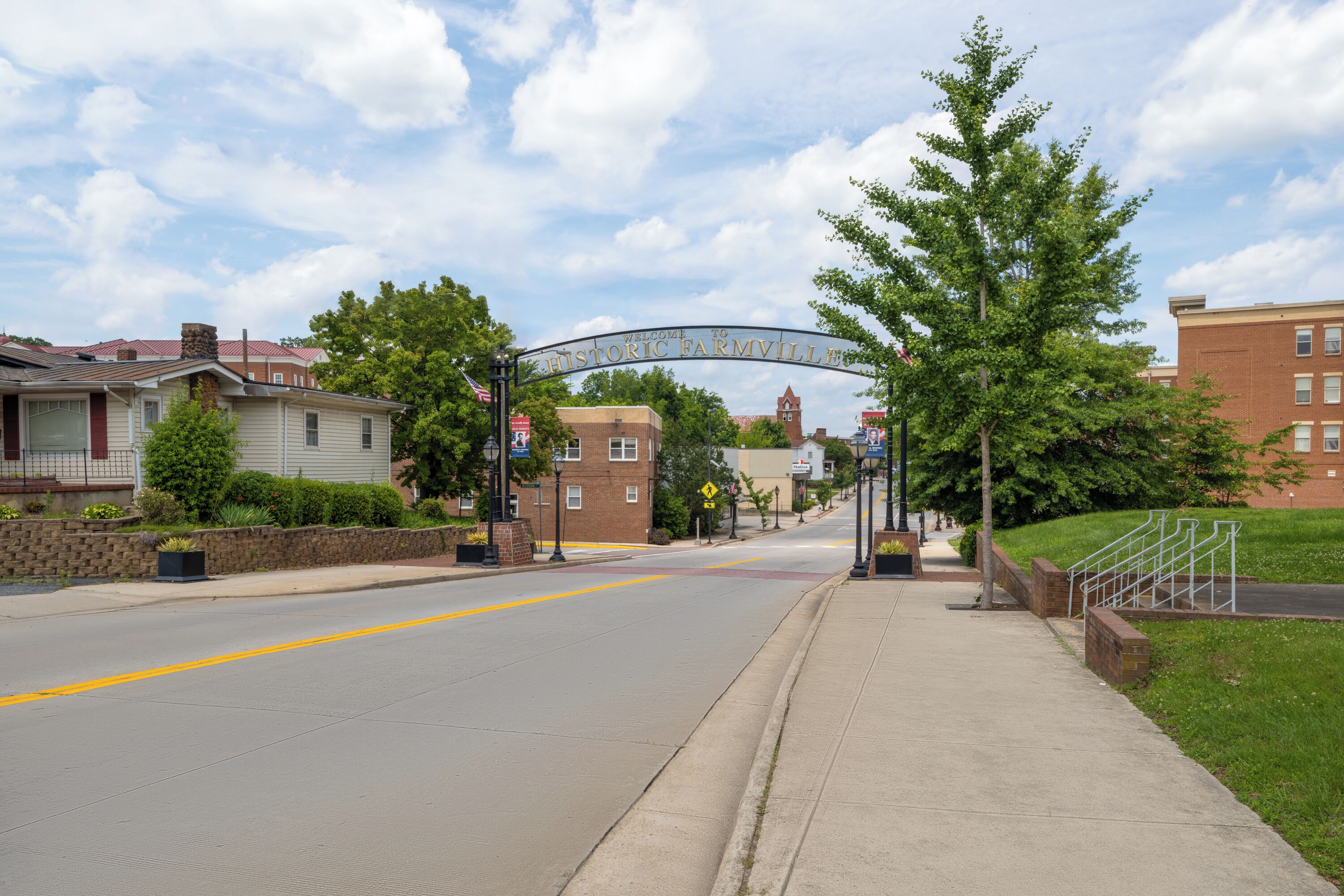 A street with a historic farmville sign, residential houses, and a brick building.