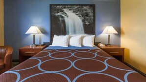 A hotel room with a large bed, two bedside tables with lamps, a chair, and a large wall painting of a waterfall. - Super 8 by Wyndham Janesville (Janesville)