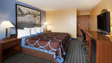 A hotel room with a bed, two bedside tables with lamps, a television, and a desk with a chair.