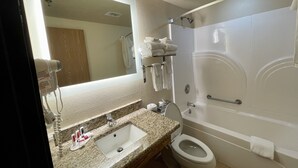 A bathroom with a sink, toilet, and bathtub. There is a towel rack with towels, a mirror, and a ceiling light.