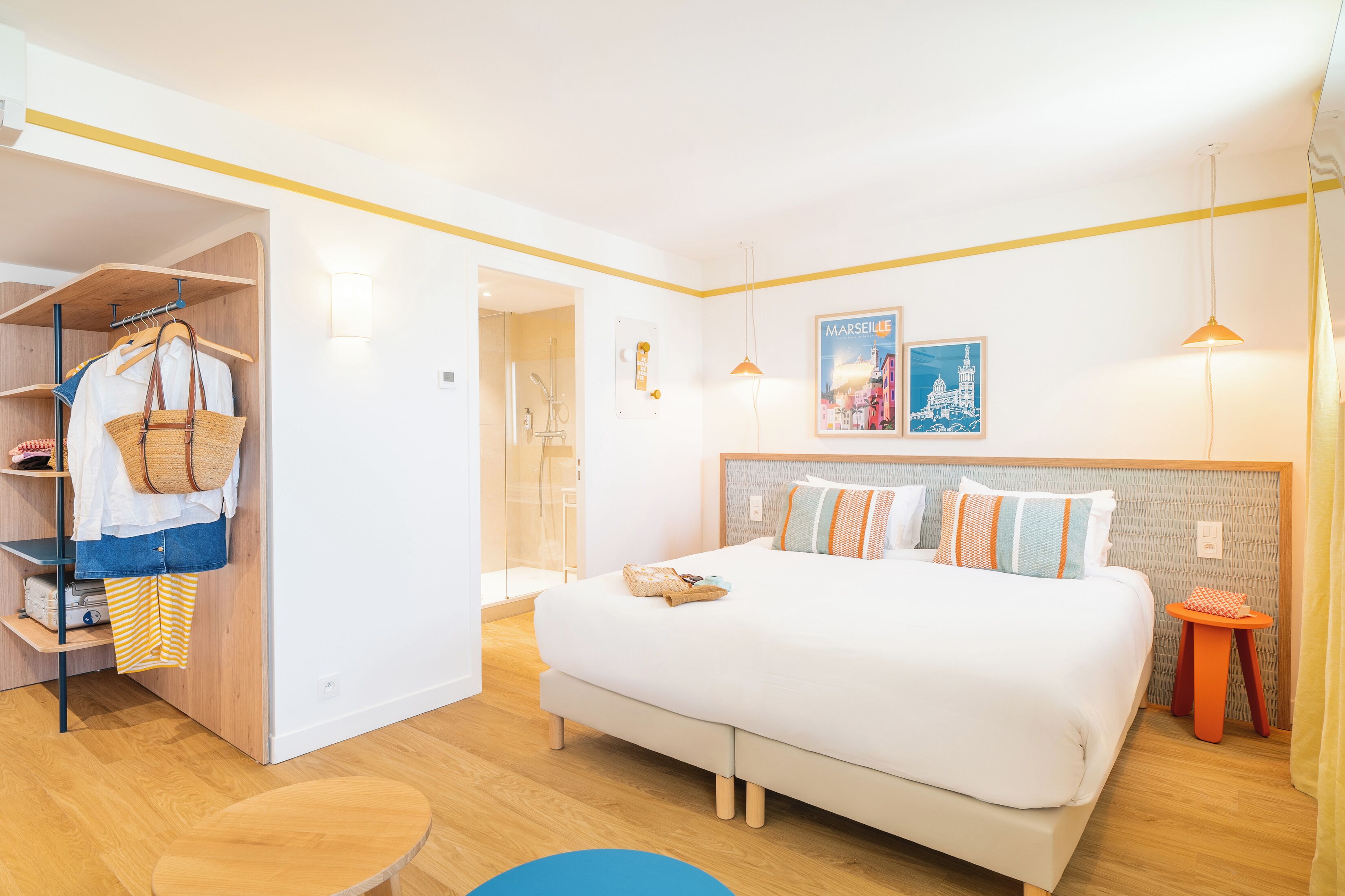 A modern hotel room with a bed, wardrobe, and a small table.