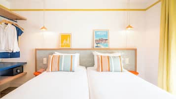 Une chambre d’hôtel avec deux lits, une armoire, un bureau et un mur orné de deux tableaux encadrés.