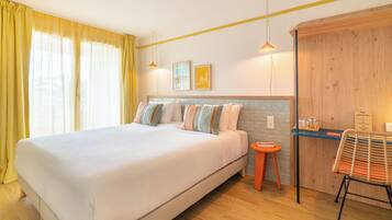 Une chambre d’hôtel avec un lit, une petite table, une chaise et une armoire en bois.