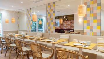 A restaurant with wooden furniture, a colorful wall, and hanging lights.