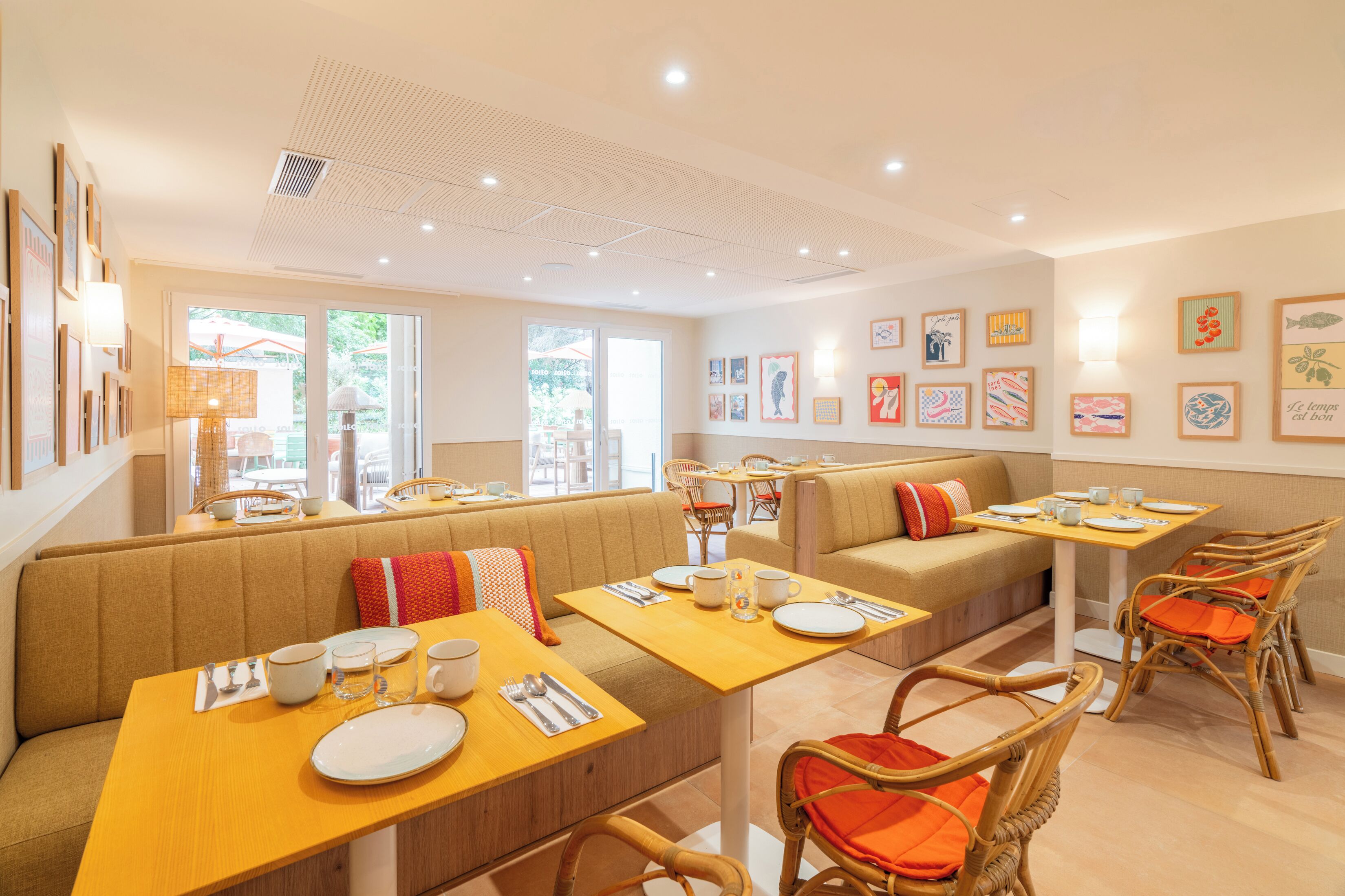 A dining area with booths and tables, equipped with cutlery and plates, and adorned with wall art.