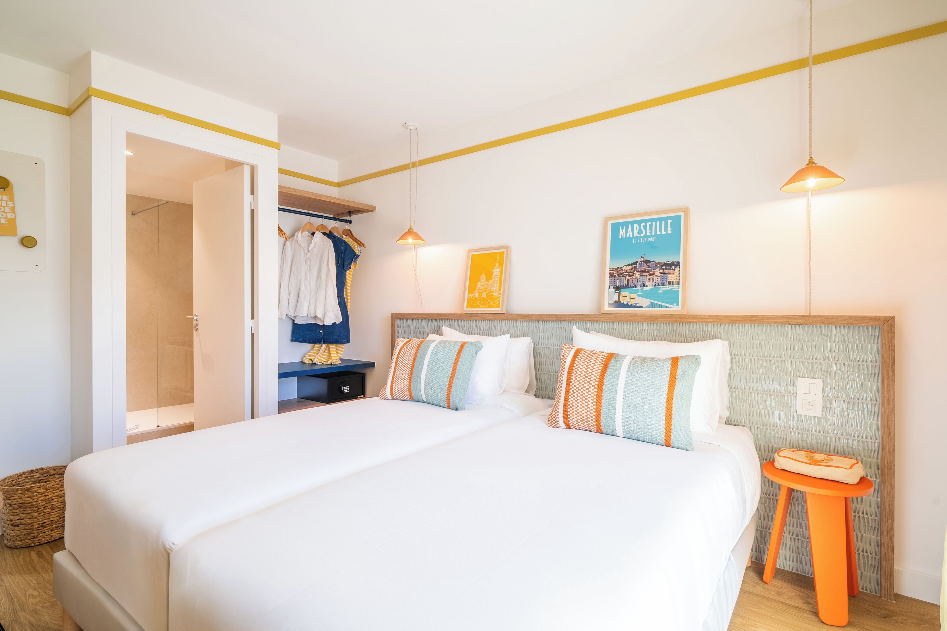 A bedroom with a large bed, a bedside table, a hanging light, a closet, and a poster on the wall.