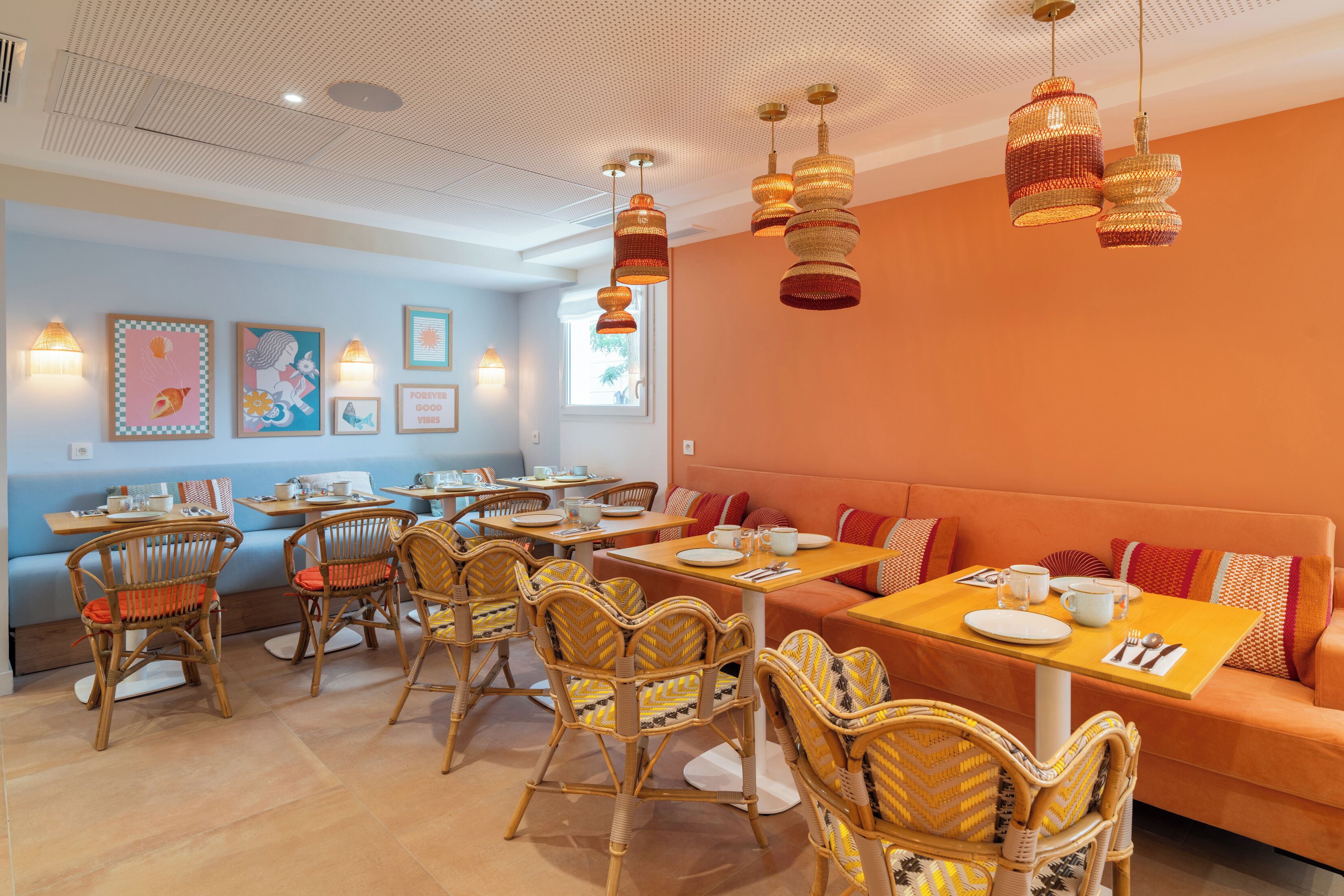 A dining area with wicker chairs, a sofa, and hanging wicker lamps.