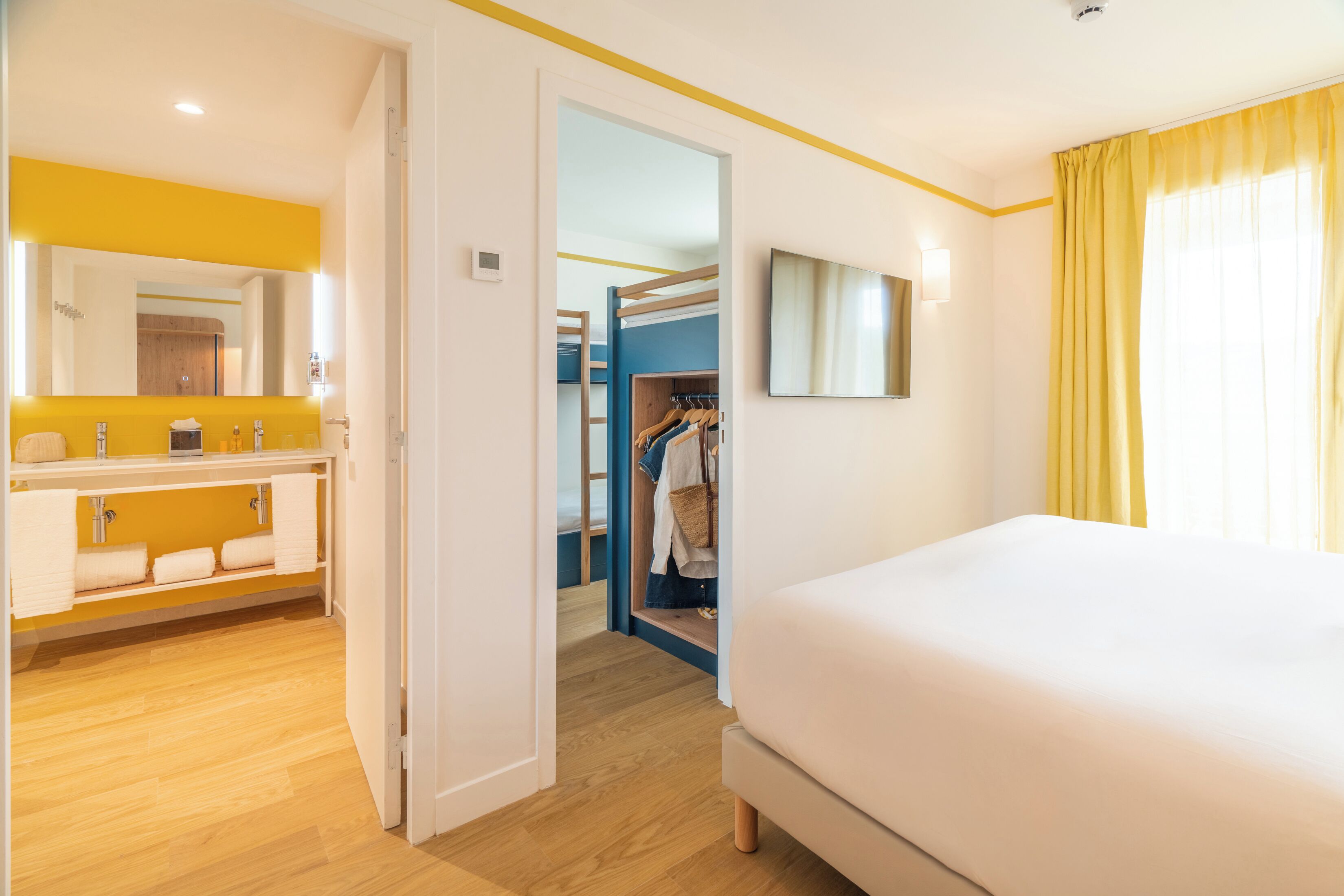Une chambre d’hôtel comprenant un lit, une salle de bain avec un miroir et un lavabo, et un dressing.