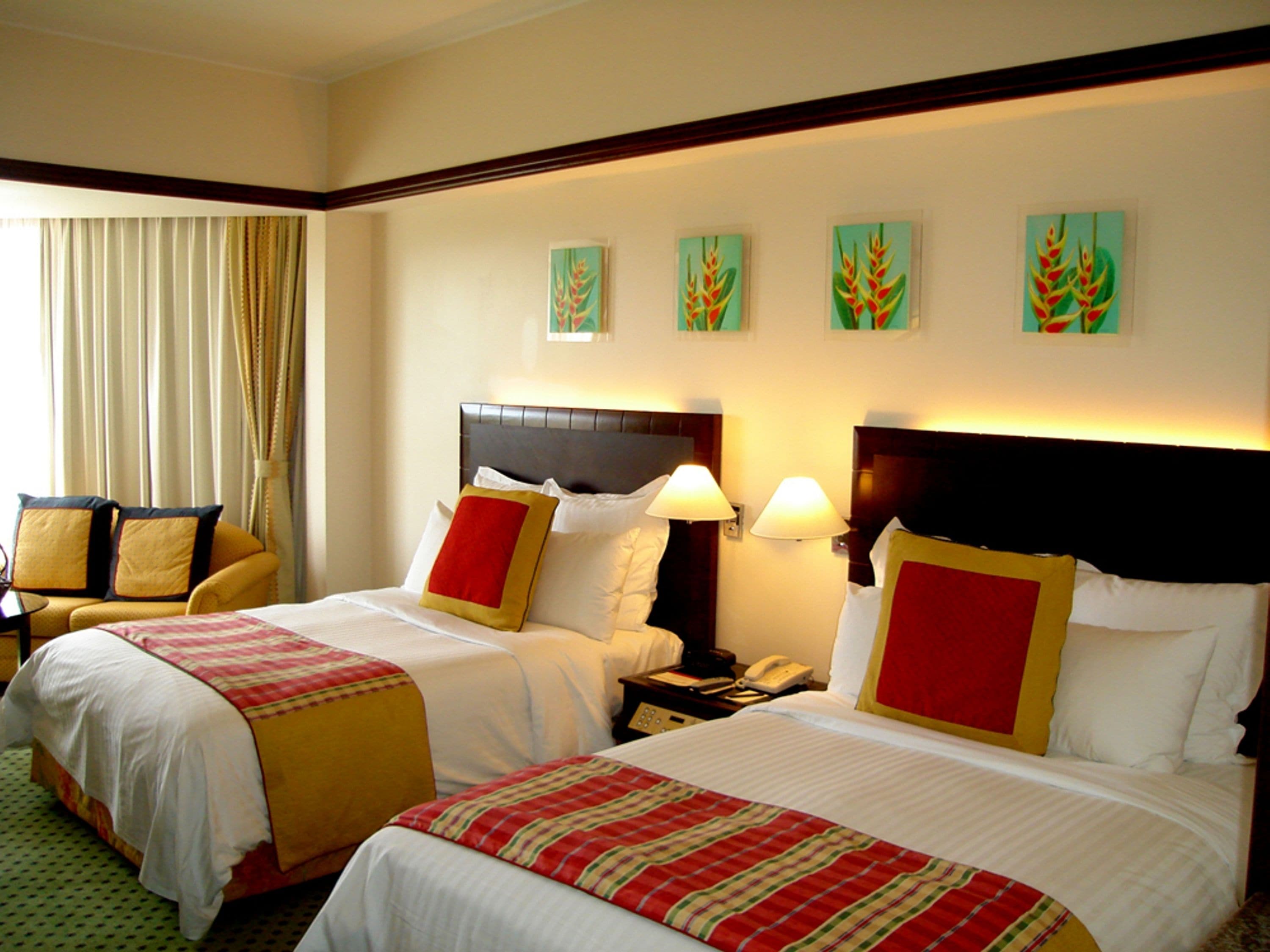 Habitación de hotel con dos camas, un sofá y obras de arte en la pared.