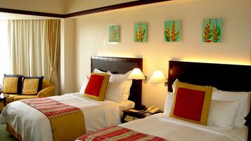 Habitación de hotel con dos camas, un sofá y obras de arte en la pared.