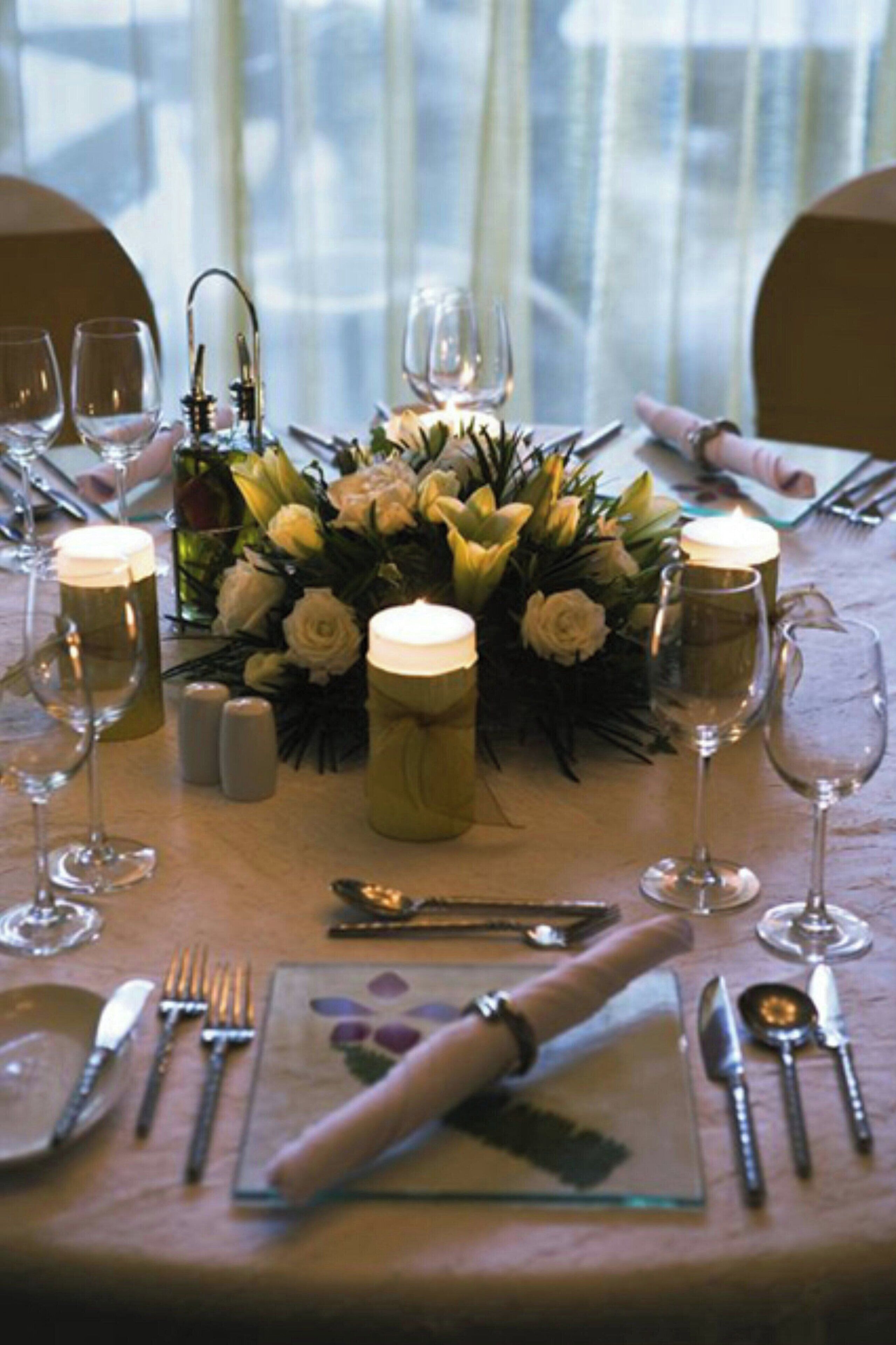 A table set for a meal with candles, glasses, and a floral centerpiece.